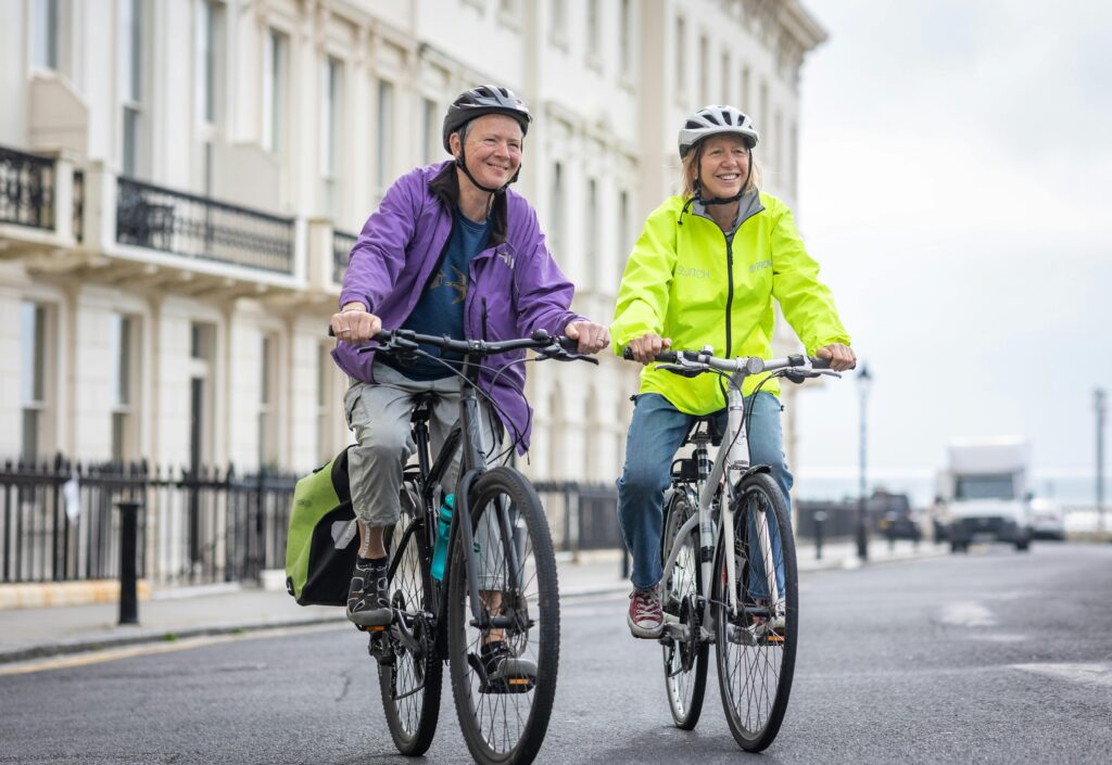 pexels-photo-21405596-21405596 Active seniors cycling on city streets wearing helmets and vibrant jackets.