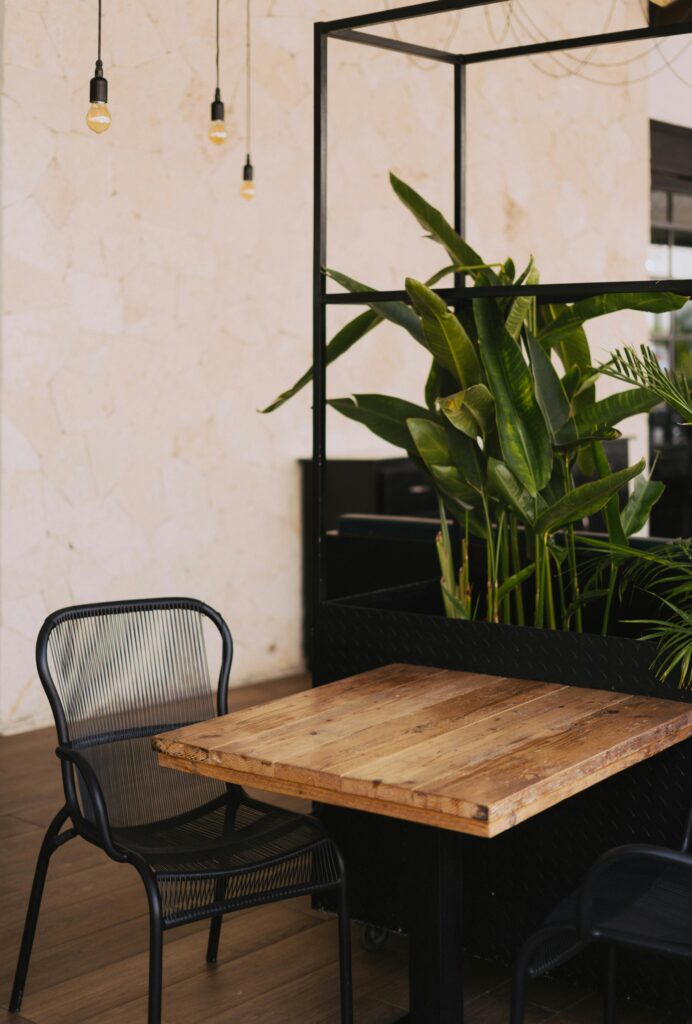 pexels-photo-2451264-2451264 Modern indoor dining area featuring wooden table and lush green houseplants.