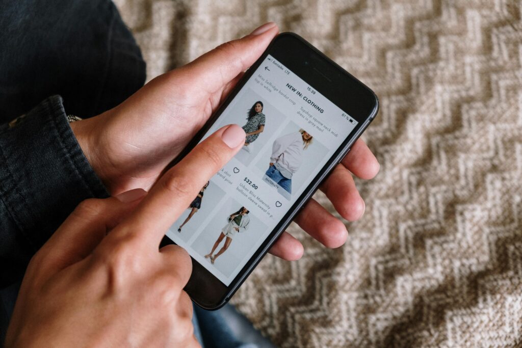 pexels-photo-5076511-5076511 Person browsing clothing items on a smartphone, showcasing modern online shopping experience.
