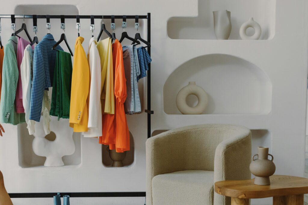 pexels-photo-8396726-8396726 A colorful variety of clothes hanging on a rack inside a contemporary room with artistic decor.
