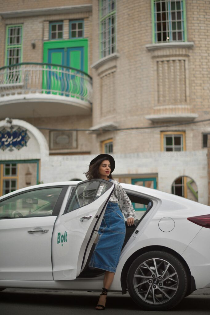 pexels-photo-9271326-9271326 A fashionable woman steps out of a Bolt ride-share vehicle in an urban setting, showcasing modern city life.