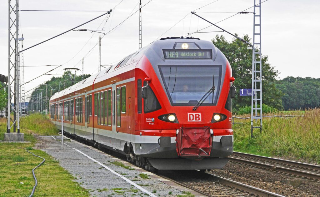 regional-train-rail-cars-platform-deutsche-bahn-159148-159148 A vibrant red electric train arrives at a rural railway station, showcasing modern public transport.