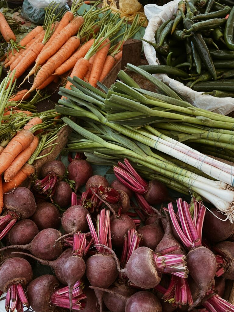 A variety of fresh vegetables including carrots, beetroots, and leeks on a market stall.